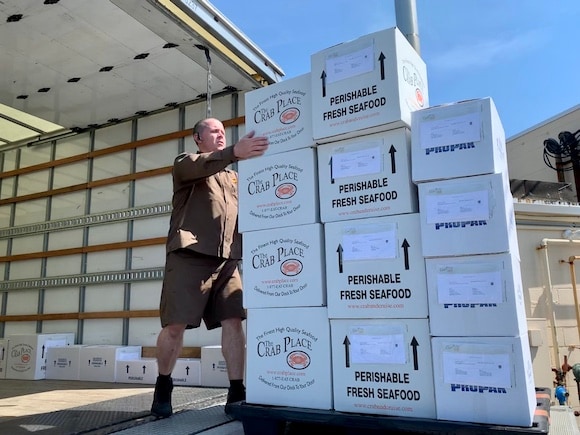 The Crab Place branded perishable seafood shipping boxes being loaded for delivery.