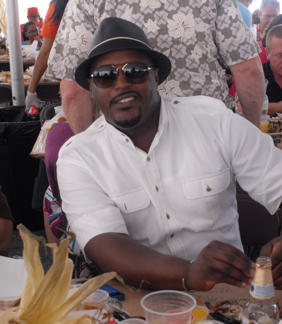 Chef Max Hardy sitting at a crab table under the event tent in Crisfield