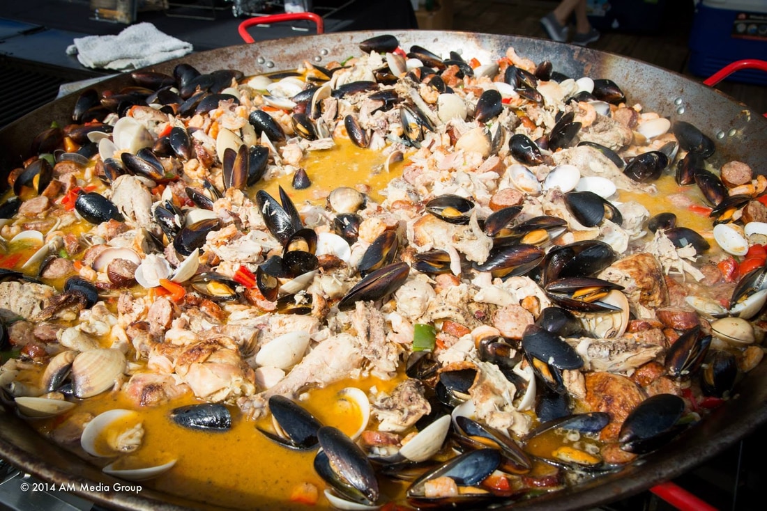Close up of a large paella pan filled with mussels, clams, shrimp and saffron rice
