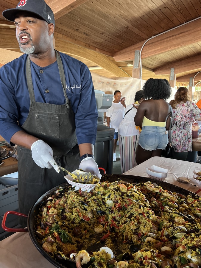 Chef Max Hardy plating his seafood paella from a pan the size of a table at the crab party in Crisfield