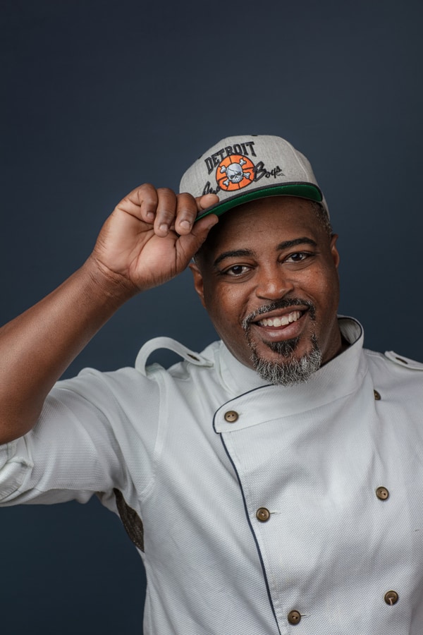 Studio portrait of Chef Maxcel Hardy in a white chef coat and a Detroit cap