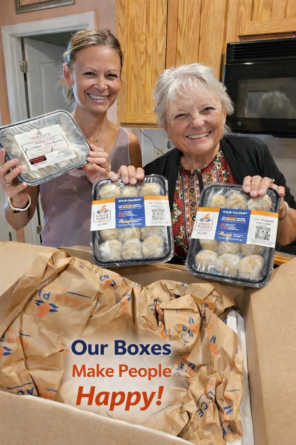 Two smiling customers in a kitchen holding trays of Crab Place 2 oz Maryland crab cakes above an open branded shipping box, with the words Our Boxes Make People Happy.