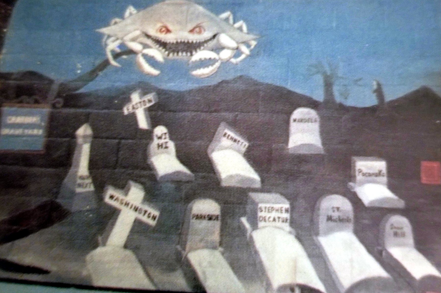 Gym wall mural of a grinning crab above a graveyard of tombstones naming rival schools.