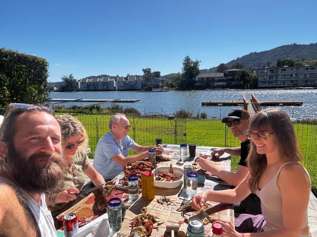 Friends cracking crabs at a table beside a lake