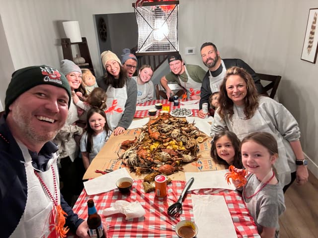 A big family crowded around a long table covered in steamed crabs