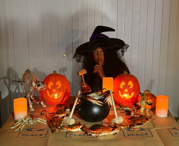 A Halloween display of jack-o-lanterns and a witch's cauldron with crabs laid out on Crab Place paper