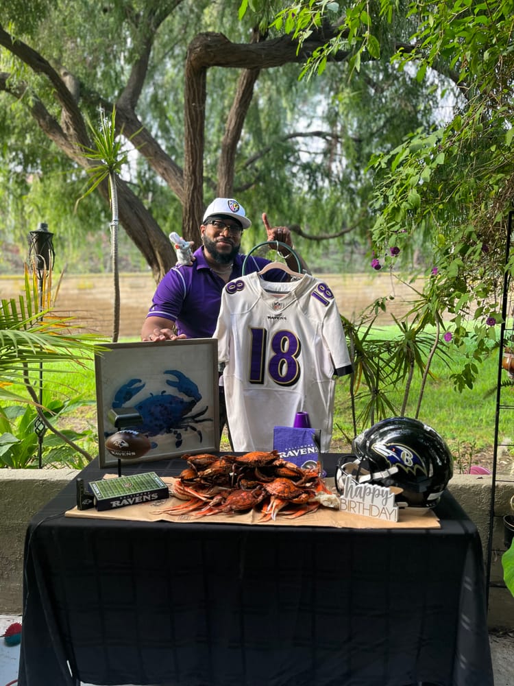 A football fan with his team's jersey and helmet set up beside an outdoor crab feast